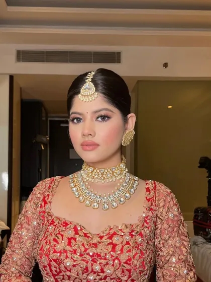 A close-up of a bride in a classic red lehenga, ready for her big day.