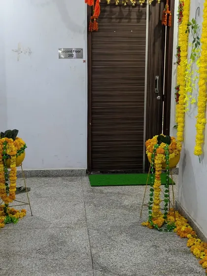 The welcome decor continues from the building entrance right up to the apartment door, with marigold arrangements creating a festive pathway for guests.