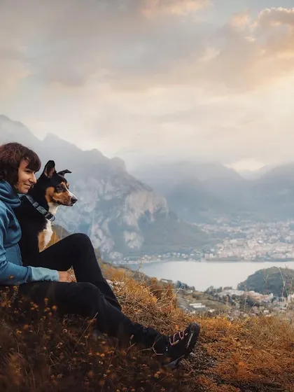 A moment of quiet reflection, watching the world go by. This image of a woman and her dog looking out over a stunning mountain lake view perfectly captures a feeling of peace and companionship.
