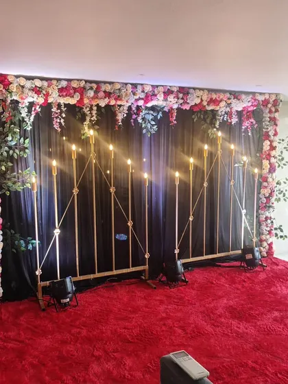 This is a stylish backdrop perfect for a Mehndi or Sangeet night. The dark curtain makes the floral arrangement and the warm, candle-style lights pop, creating a dramatic and beautiful photo corner.