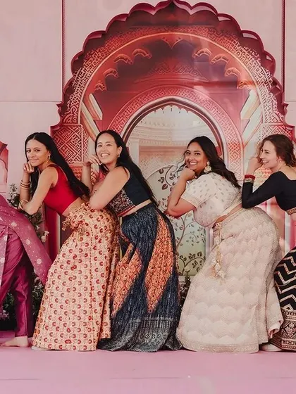 The joy of friendship on full display. The bride and her friends strike a playful pose against the royal-themed Sangeet backdrop, creating a fun and vibrant memory.