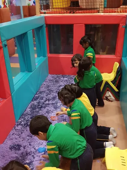 A moment of focused, creative play in the kinetic sand pit during a school outing. It's a great calming activity amidst all the high-energy fun.
