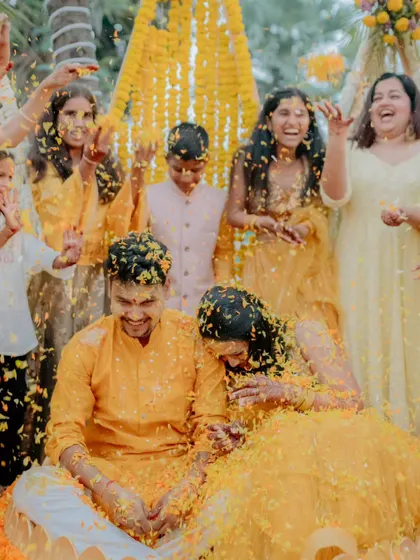 A moment of pure fun as the couple is showered with marigold petals by their loved ones during the Haldi ceremony. The decor, with its focus on traditional yellow flowers, enhances the authenticity of the ritual.
