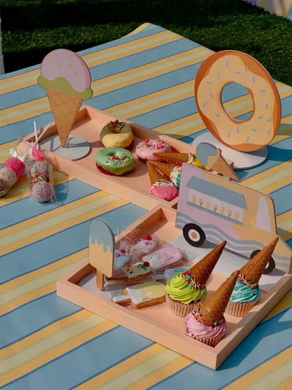 A tray of whimsical desserts, including ice cream-cone cupcakes and donut-themed cookies.