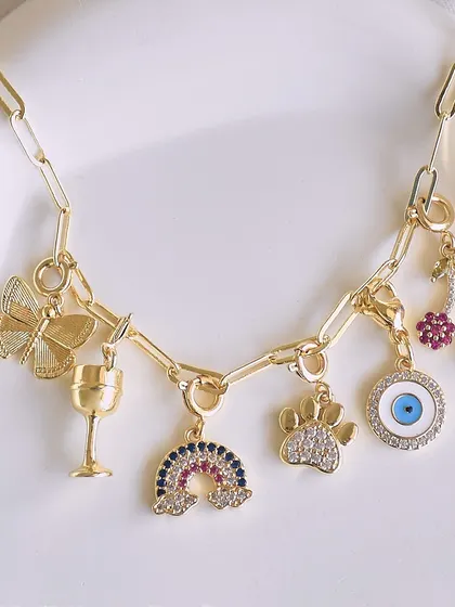 This playful charm combination features a butterfly, a wine glass, a rainbow, a paw print, and an evil eye. It's a perfect example of how you can mix your passions on one chain.