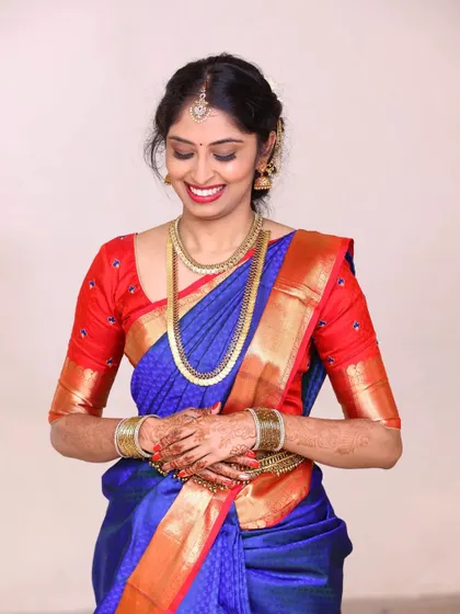 For Akshatha's engagement, we chose a classic look with a simple hairstyle and makeup that highlighted her smile. The royal blue and red of her saree are beautifully balanced with neutral, warm makeup tones.
