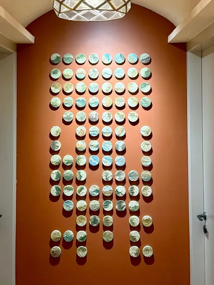 A direct view of the 100 little landscapes installation. The pieces are arranged in a unique pattern, creating a visually stunning effect on the accent wall.