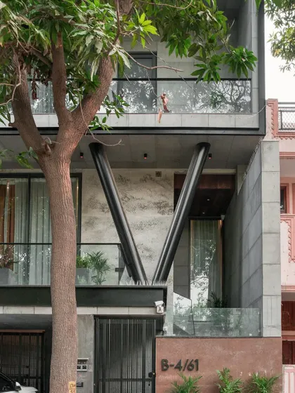 A daytime detail of the Paschim Vihar residence. The angled steel columns provide structural support while acting as a powerful design element, contrasting with the raw concrete and glass.