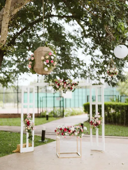 An understated yet beautiful entrance setup. The clean white frames are decorated with soft florals, and hanging floral baskets from the tree above add a touch of whimsical charm.