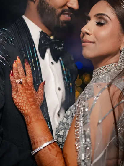 A close-up, intimate portrait of Amrita and Ketan. This shot focuses on the bride's henna-adorned hand and the couple's loving gaze, capturing a moment of quiet connection.