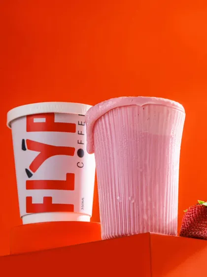 A strawberry milkshake from Flyp, styled with a similar overflowing drip effect. This technique creates a sense of abundance and delicious messiness.