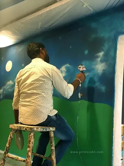 Our artist sits focused while adding details to a night sky mural. Creating large-scale art requires both artistic vision and the patience to bring it to life, step by step.