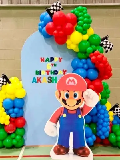 A fun Super Mario themed backdrop with a large Mario cutout and a balloon arch in the game's signature colors.