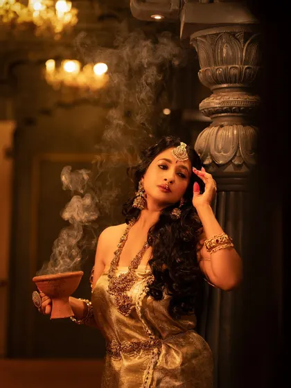 An artistic shot of Manvita Kamath holding a traditional incense burner, with smoke swirling around her. This adds a mystical element to the photoshoot.