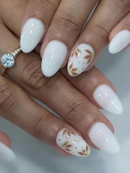 A clean and classic bridal look. This design features milky white almond-shaped nails with two accent nails showcasing delicate, hand-painted gold leaf patterns.