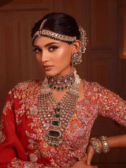 A full-length view of a bride in a magnificent red lehenga. I teach my students to have a vision for the entire look, ensuring the makeup, hair, and outfit come together perfectly.