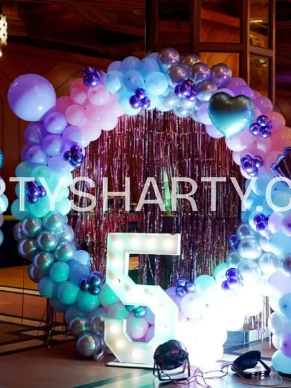 A circular balloon arch in ocean colors creates a perfect photo spot, complete with a large light-up number '5' for the birthday girl.