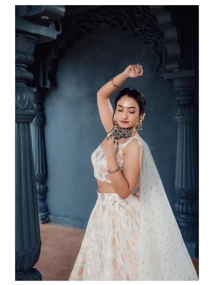 The model in a graceful pose, showing the flow of the off-white lehenga and dupatta.