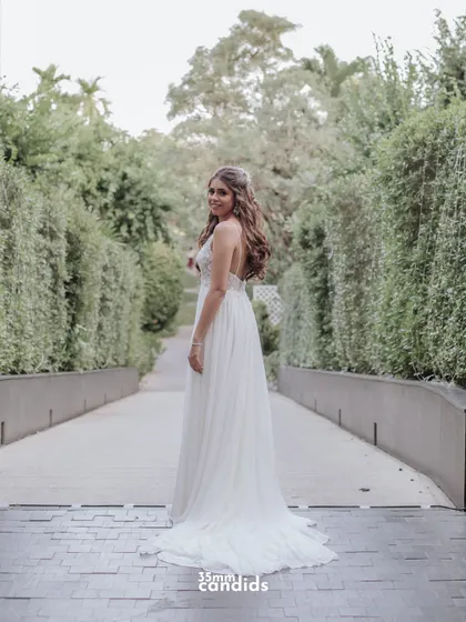 A full-length shot of Trisha in her flowing white gown, looking back with a smile. A beautiful and classic bridal portrait.