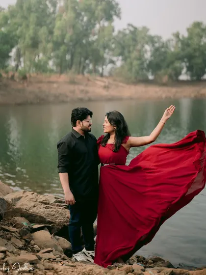 The wind catches her dress as she and Shubham share a look by the lake, creating a dynamic and romantic pre-wedding image.