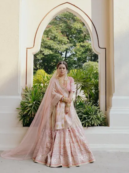 A full-length portrait of Apurva, showcasing her stunning Tarun Tahiliani lehenga against a classic archway. I focus on capturing the artistry of bridal couture.
