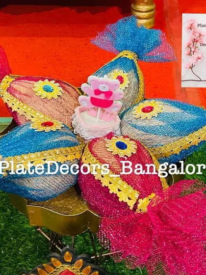 Coconuts wrapped in pink and blue net fabric with a small teddy bear candle. This is a budget-friendly yet charming decoration for a baby shower.