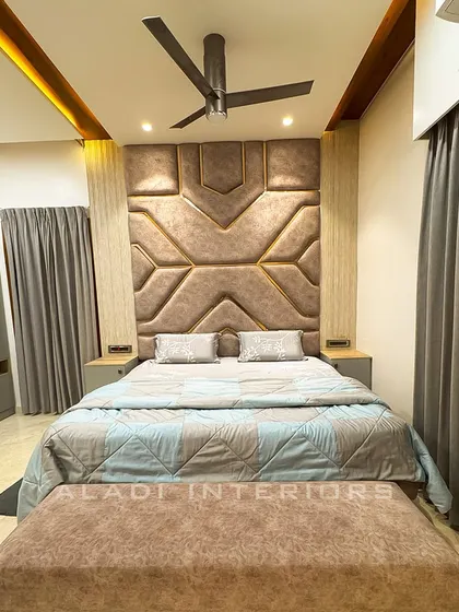 A stunning bedroom with a large, geometric-patterned upholstered headboard in a soft brown fabric. The matching bench and bedding create a luxurious and cohesive look.