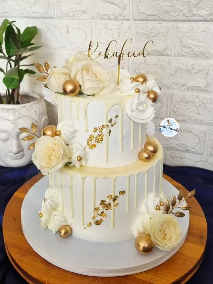 This two-tier Roka cake is all about classic elegance. I used a white-on-white drip effect, delicate white roses, and touches of gold leaf and spheres to create a timeless and luxurious look.