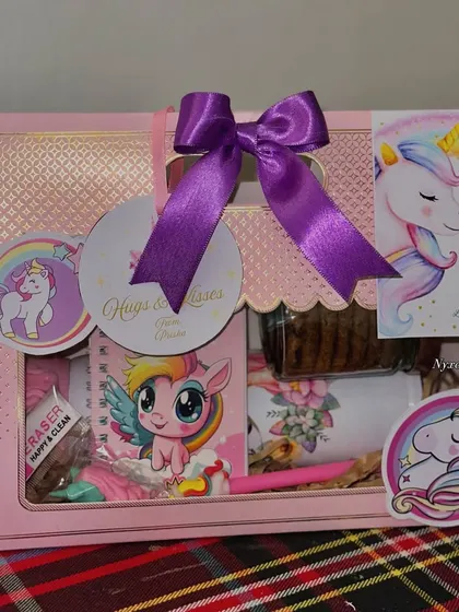 A closer look at the Unicorn-themed version of our kids' hamper. This one features a cute notebook, pen, eraser, and other treats, all tied together with a lovely purple bow.