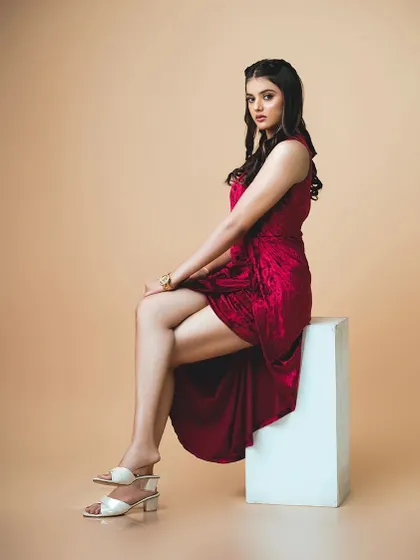 Another seated pose showing the stylish cut of the red velvet party dress.