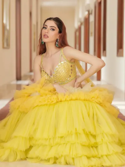 Sunshine in a frame. This tiered, ruffled yellow lehenga by Liz Paul is styled for a fun and vibrant Haldi or Mehendi ceremony. The look is playful, modern, and full of energy.