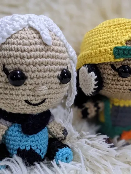 A pair of crochet dolls inspired by the Valorant characters Jett and Raze, sitting together.