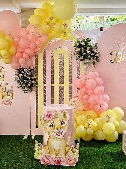 A full view of Dua's second birthday setup. The pink and yellow lion cub theme included 'TWO' letter blocks, a large balloon arch, and multiple character cutouts for a sweet and playful look.