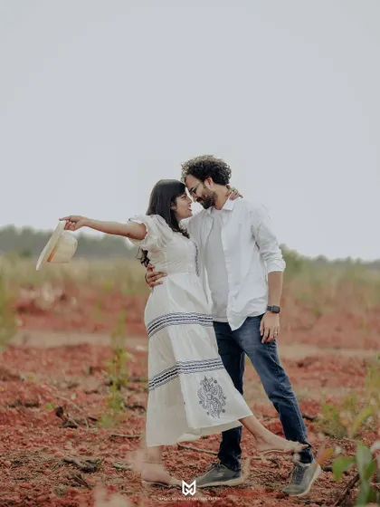 A playful and romantic moment from Ankita and Rajat's outdoor pre-wedding shoot. Her gesture of taking off her hat adds a touch of spontaneity to the pose.