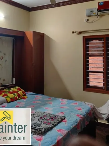 A bedroom with beige walls and polished wood furniture and window frames. The neutral wall color makes the room feel warm and cozy.
