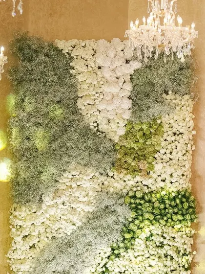 A floral wall created with a textured mosaic of white and green blooms. This installation served as a stunning photo backdrop, showcasing the beauty of simplicity and meticulous craftsmanship.