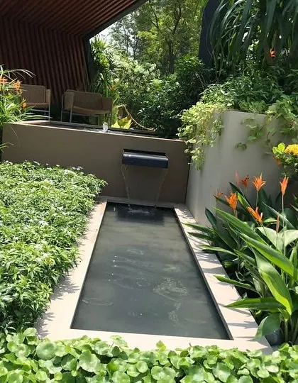 A close-up of the water feature in our modern garden project. The gentle sound of the waterfall adds a layer of tranquility, while the surrounding ground cover and Bird of Paradise plants provide a lush, tropical feel.