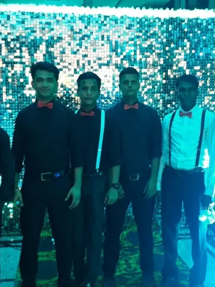 My service staff in a modern uniform of black shirts, bow ties, and suspenders, posing in front of a sequin backdrop.