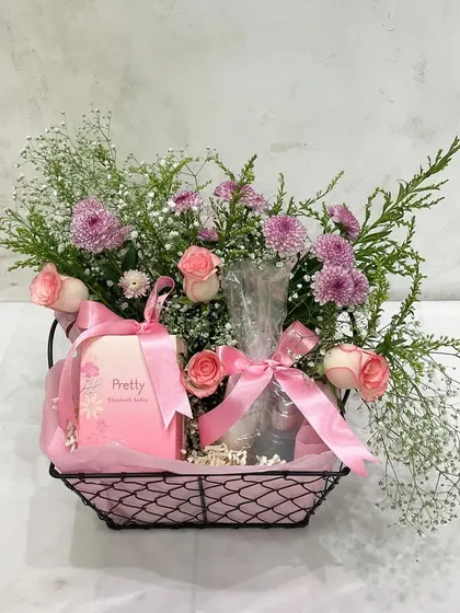Pretty in pink for Mother's Day. This simple black wire basket holds a few thoughtful gifts and is elevated by a beautiful arrangement of pink roses and chrysanthemums.