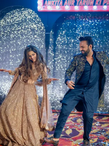 A couple lost in their own world on the dance floor. The Bollywood-themed Sangeet decor, with its glittering backdrop and custom marquee, created the perfect atmosphere for romance.