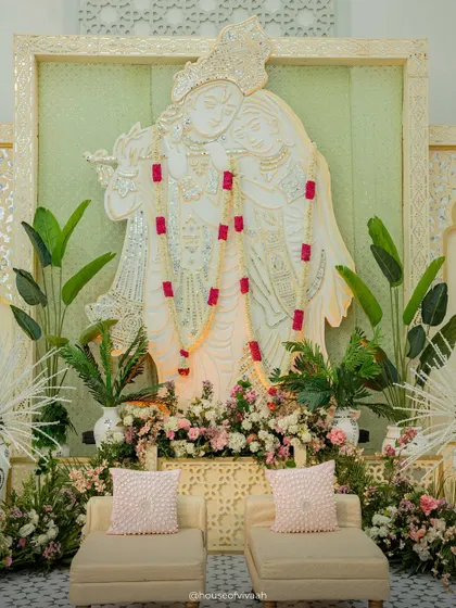 The central Radhe Krishna installation, framed by mosaic panels and adorned with a simple garland, serving as a serene and spiritual focal point for the Haldi.