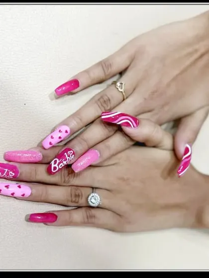 Another shot of the long, square-shaped Barbie nails, featuring different designs on each nail, including hearts, glitter, and the iconic logo.