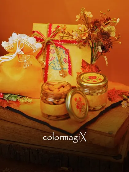 This rustic-themed tray hamper is perfect for Diwali. It includes a decorative box, a potli bag, and jars of cashews and other treats, all arranged on a wooden platter.