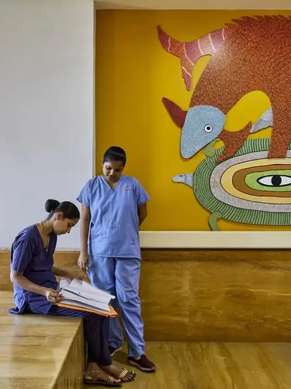 Informal interactions in a sunlit corridor of the JSW Sanjeevani Hospital. We design these transitional spaces to be wide and comfortable, with built-in seating to encourage moments of rest and conversation for staff and patient families.