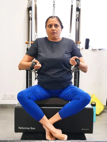 This client demonstrates a seated row on the reformer box. Pilates is a perfect low impact exercise for those over 40, as it strengthens the core, enhances flexibility, and protects the joints.
