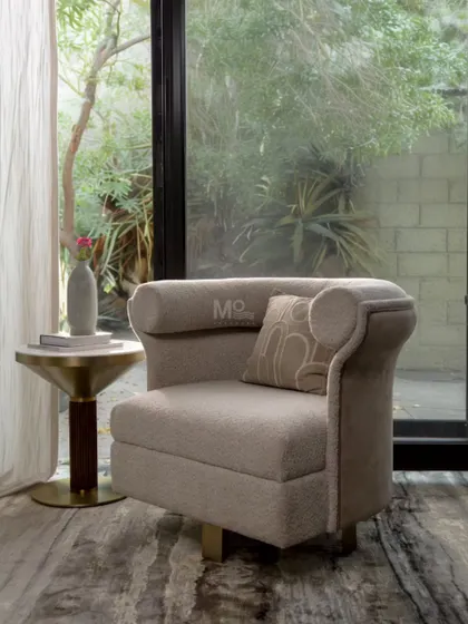 This is the Sienna Curve Armchair, with its distinctive curved backrest inspired by modernist lounges. Upholstered in a luxurious bouclé with a smooth velvet accent, its gold-toned metal base allows for a 360-degree swivel.