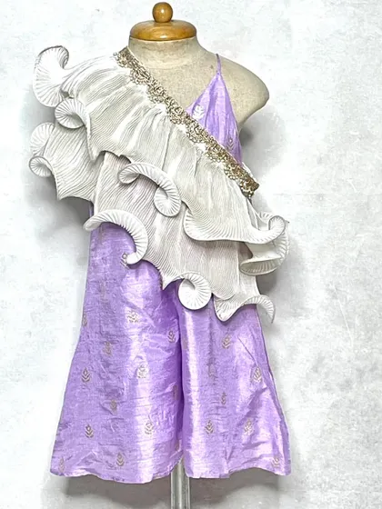 A modern take on festive wear. This lavender jumpsuit features a stunning, sculptural white frill that drapes over the shoulder, creating a high-fashion ethnic look.