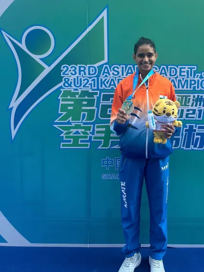 Ms. Rusha Tambat proudly displays her silver medal and the event mascot at the 23rd Asian Karate Championship. These moments of international success are what we strive for.