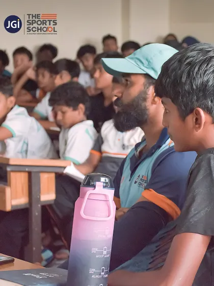 A coach sits with students in a classroom, bridging the gap between on-field practice and theoretical knowledge.