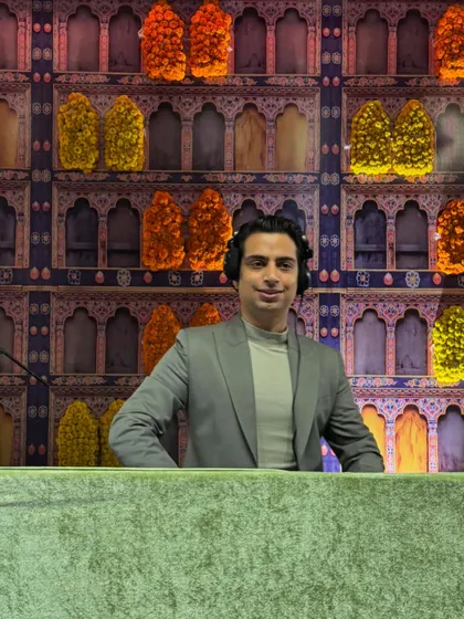 A happy moment behind the console at a mehndi function. The colorful, traditional backdrop filled with flowers perfectly reflects the joy of the event.